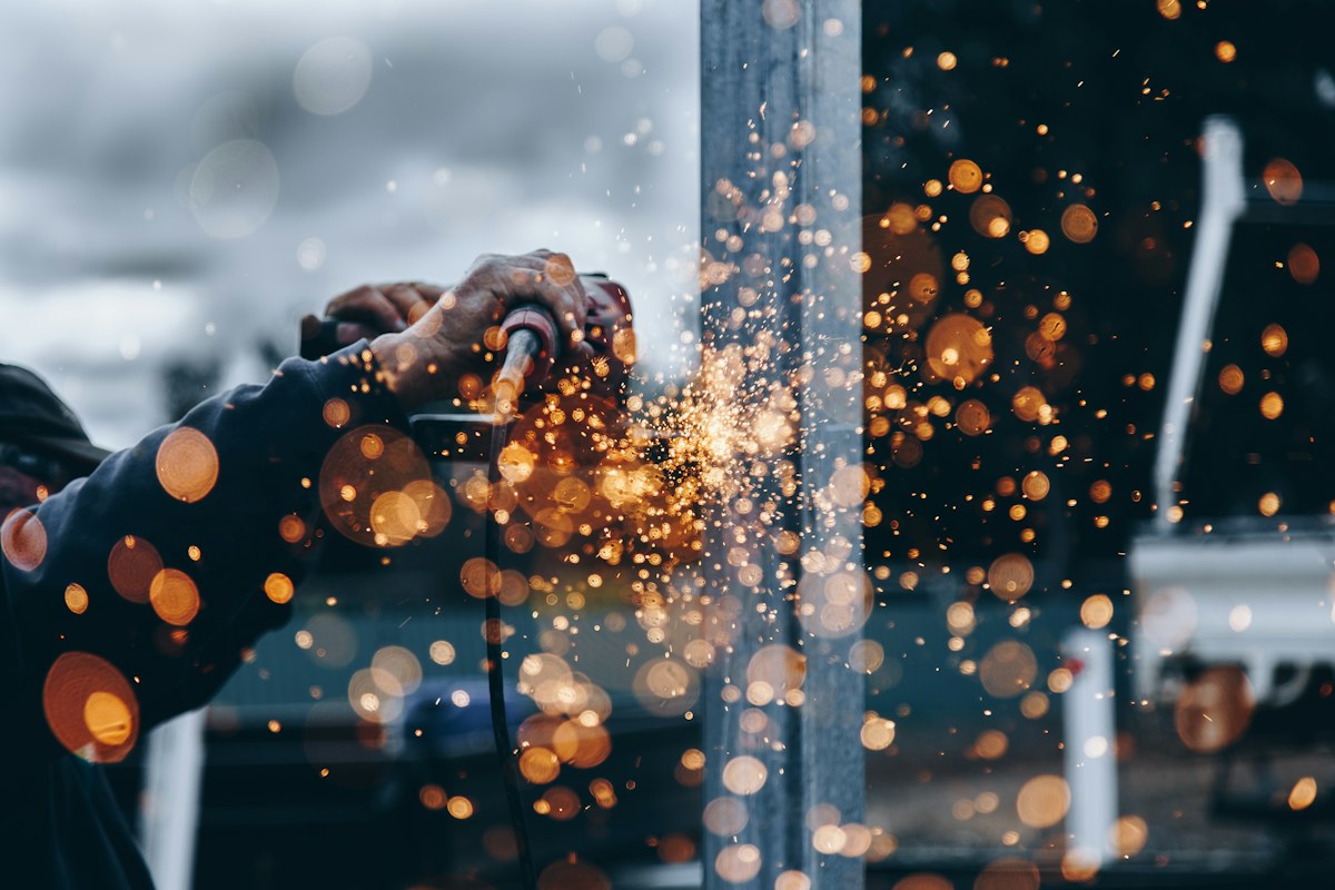A worker using a powered tool on a metal structure